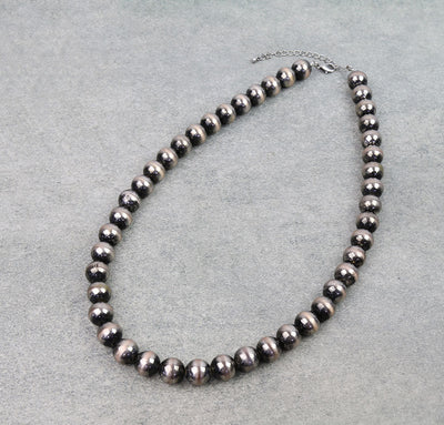 Necklace with black beads on a gray background