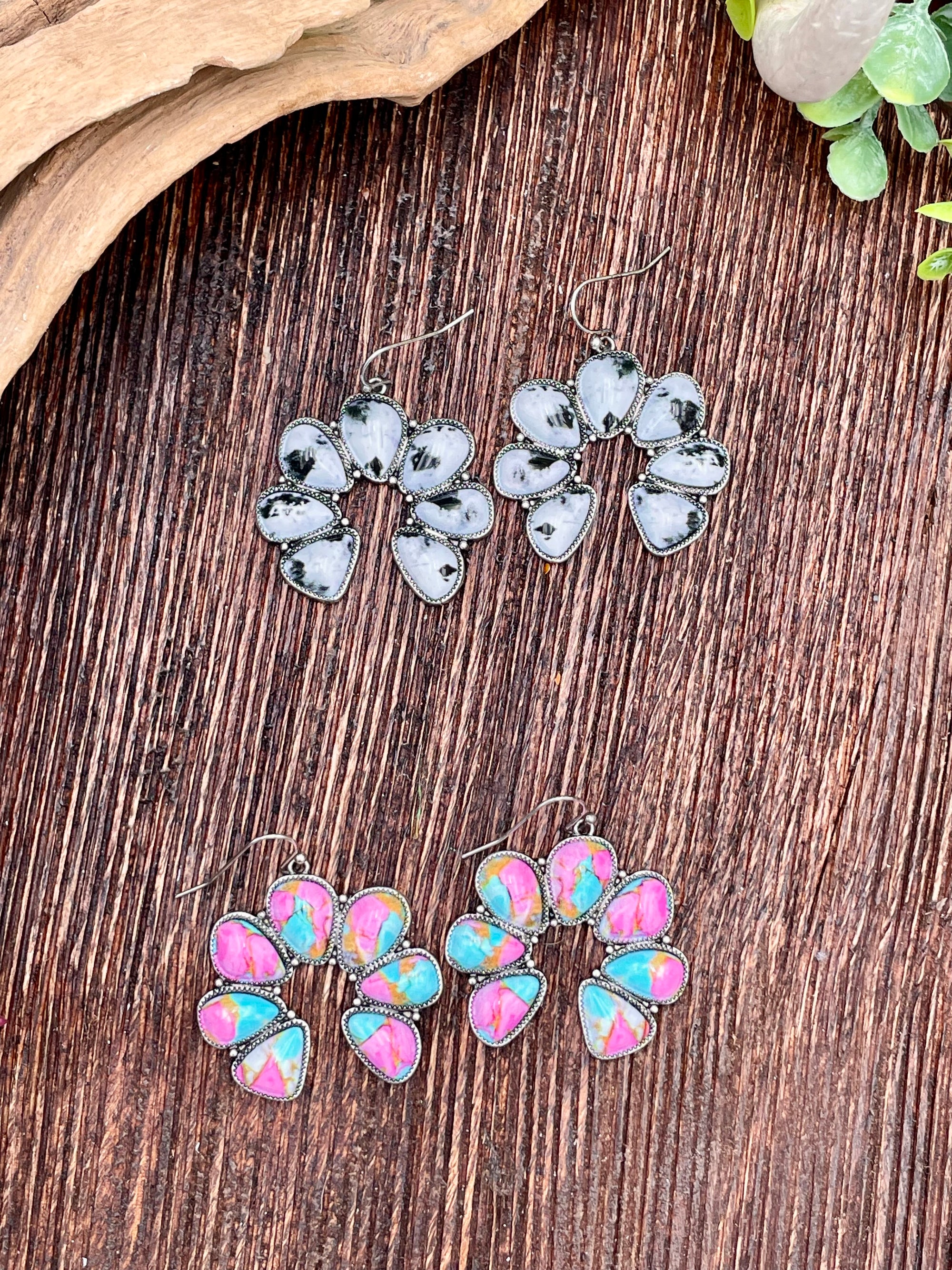 Two pairs of Naja earrings on a wooden surface