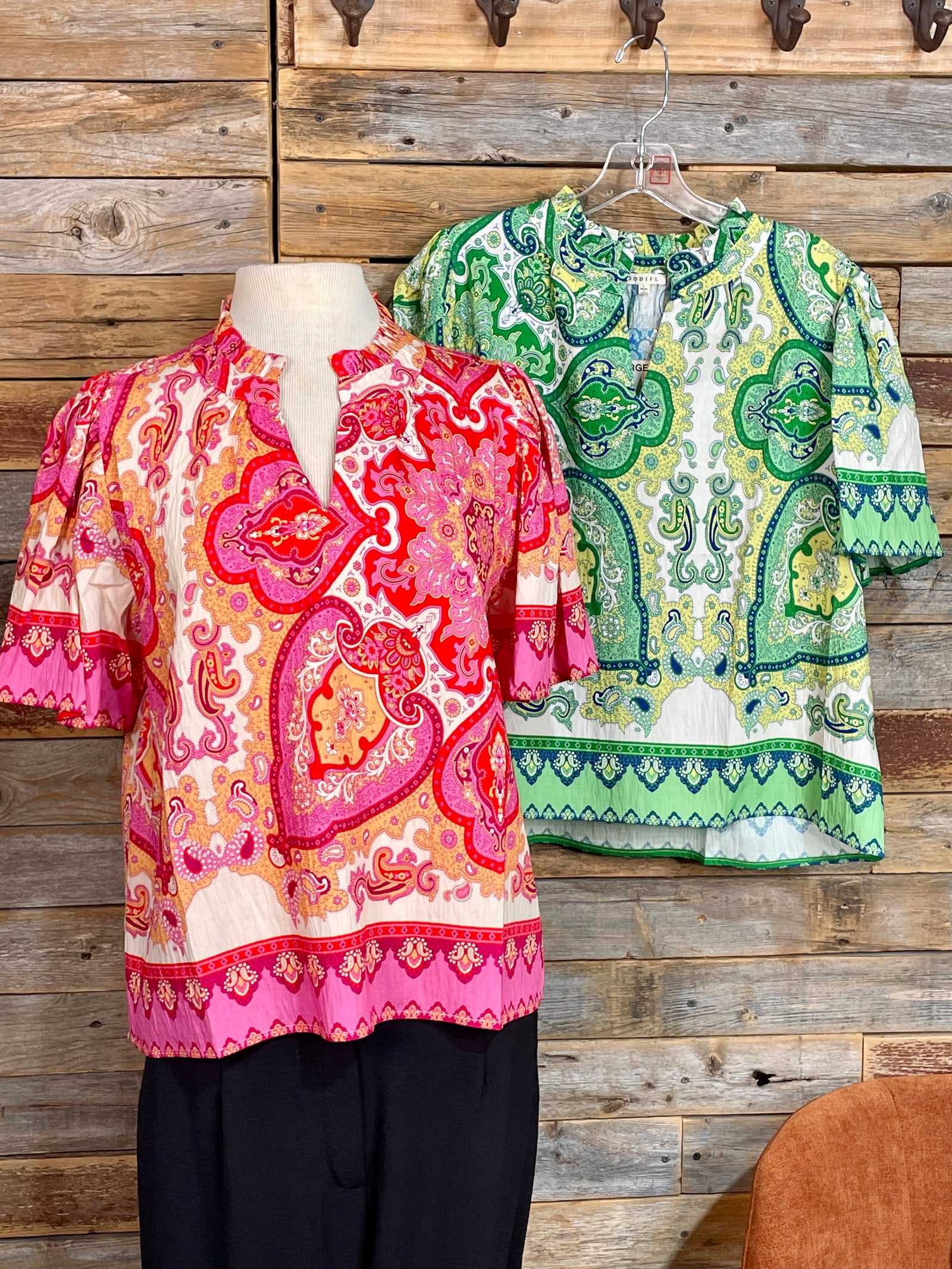 Two patterned tops displayed against a wooden wall.