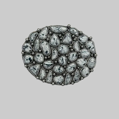 Decorative brooch with teardrop-shaped stones on a textured gray background