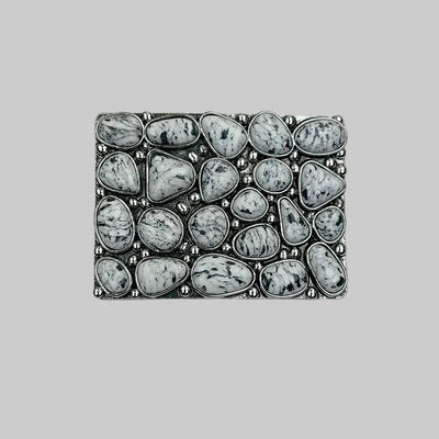 Decorative stone-encrusted belt buckle on a textured gray background