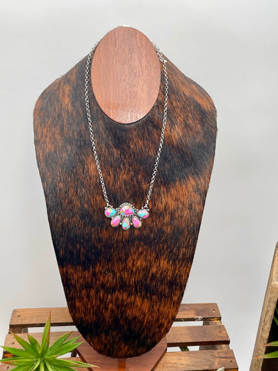 Necklace with pink and turquoise stones on a wooden mannequin bust against a white background