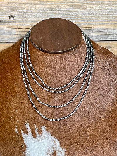 Necklace with multiple strands on a mannequin bust against a wooden background