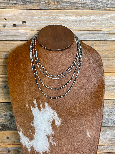 Set of 4 necklaces displayed on a brown and white cowhide against a wooden background