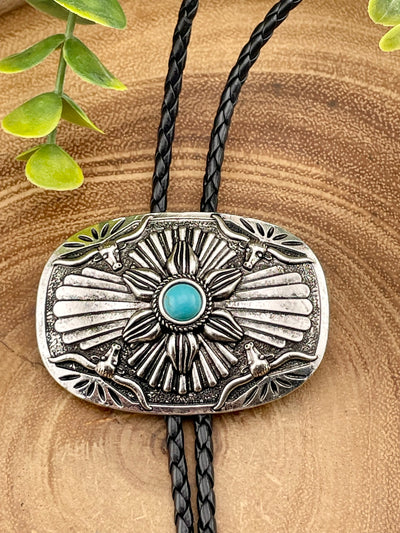 Silver bolo tie with turquoise stone on a wooden surface