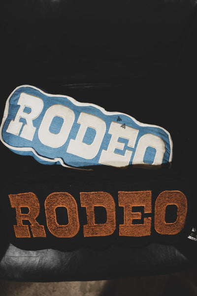 Two 'RODEO' patches, one blue and white, one brown, on a dark background.