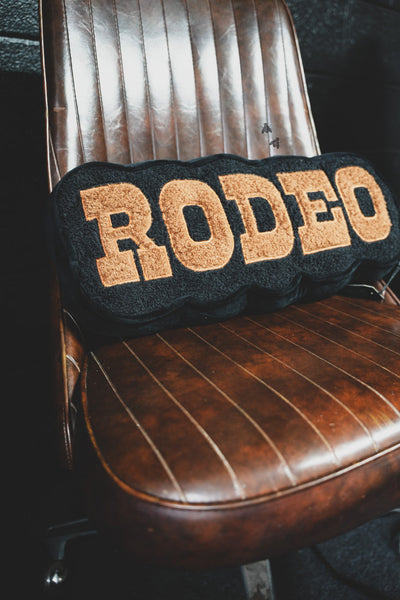 Decorative pillow with 'RODEO' text on a leather chair