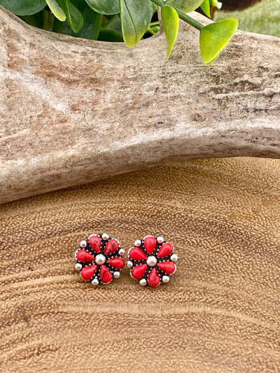 Floral stud earrings with red and silver design on a wooden surface