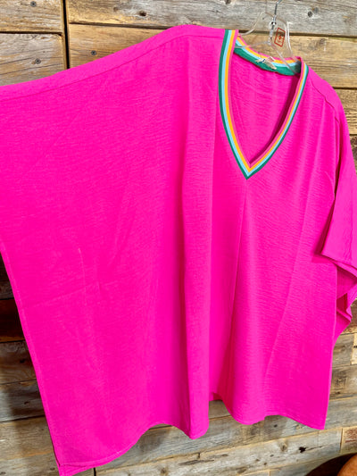 Pink shirt with a colorful neckline on a wooden surface