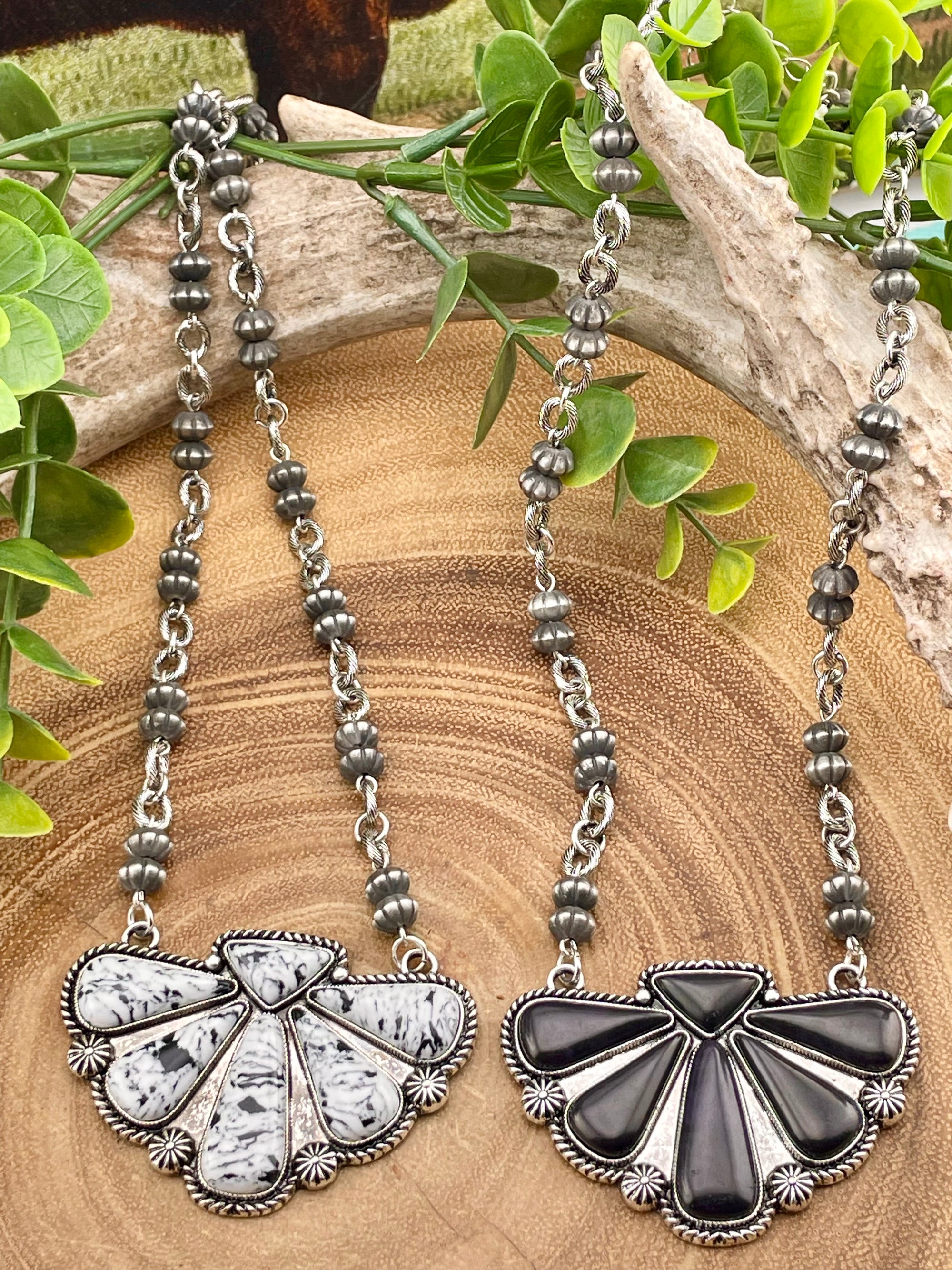 Pair of silver necklaces with leafy green background