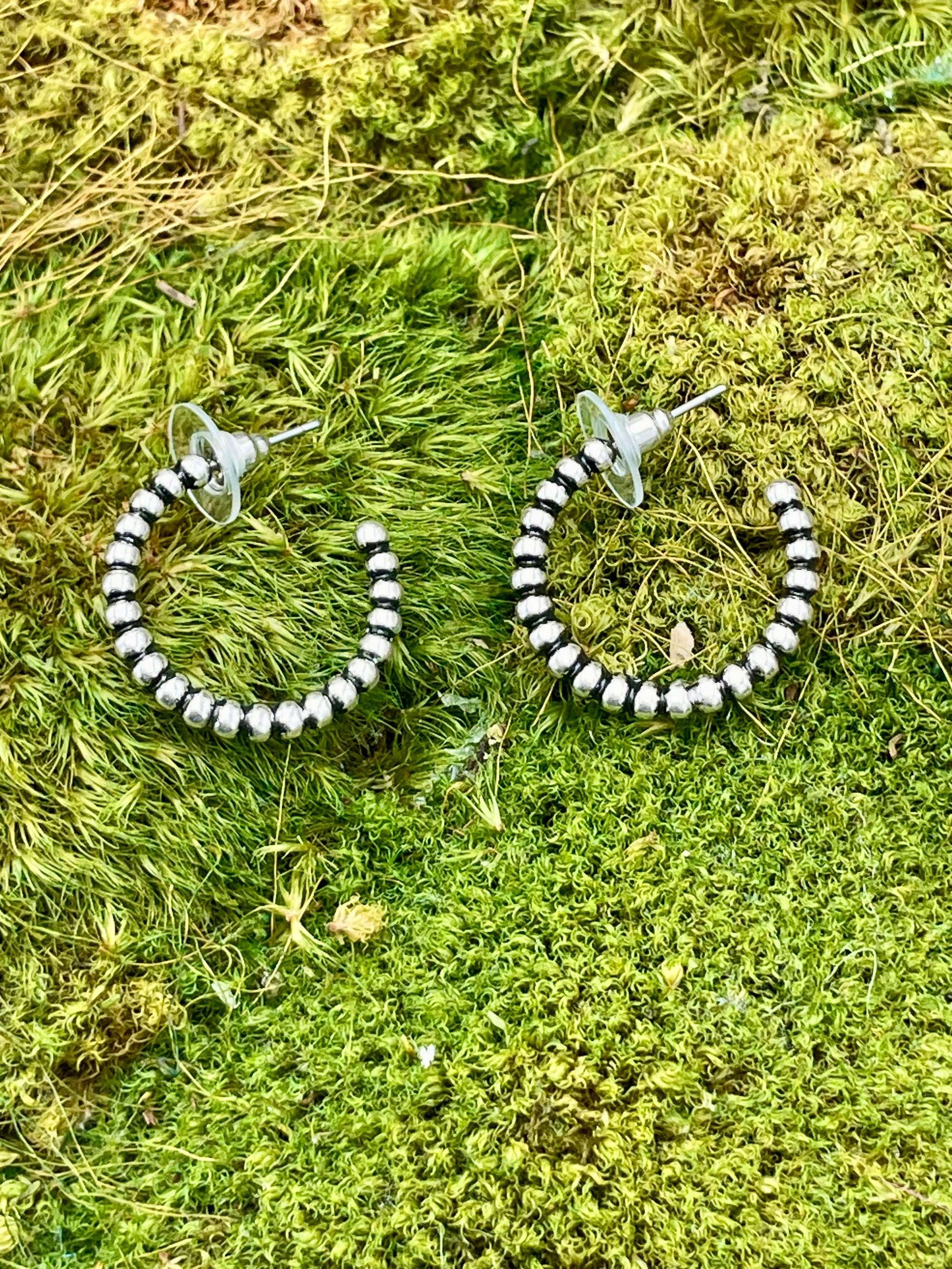 Silver hoop earrings on a green moss background