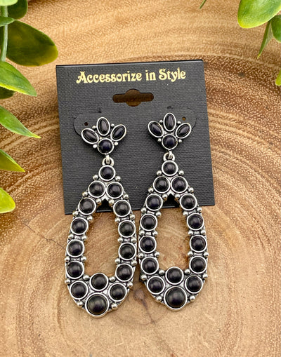 Black and silver earrings on a 'Accessorize in Style' card with a wooden background