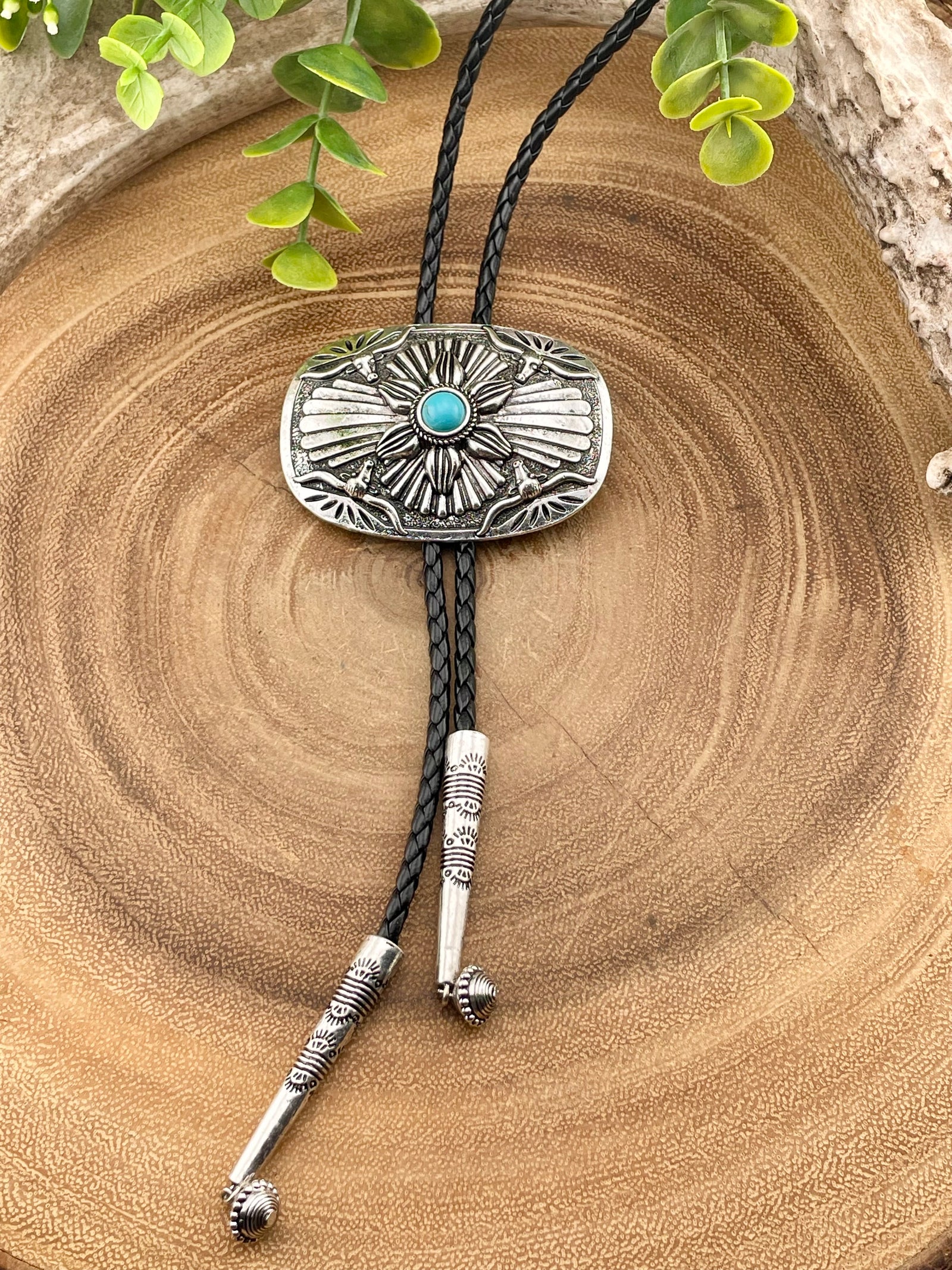 Silver bolo tie with turquoise stone on a wooden surface