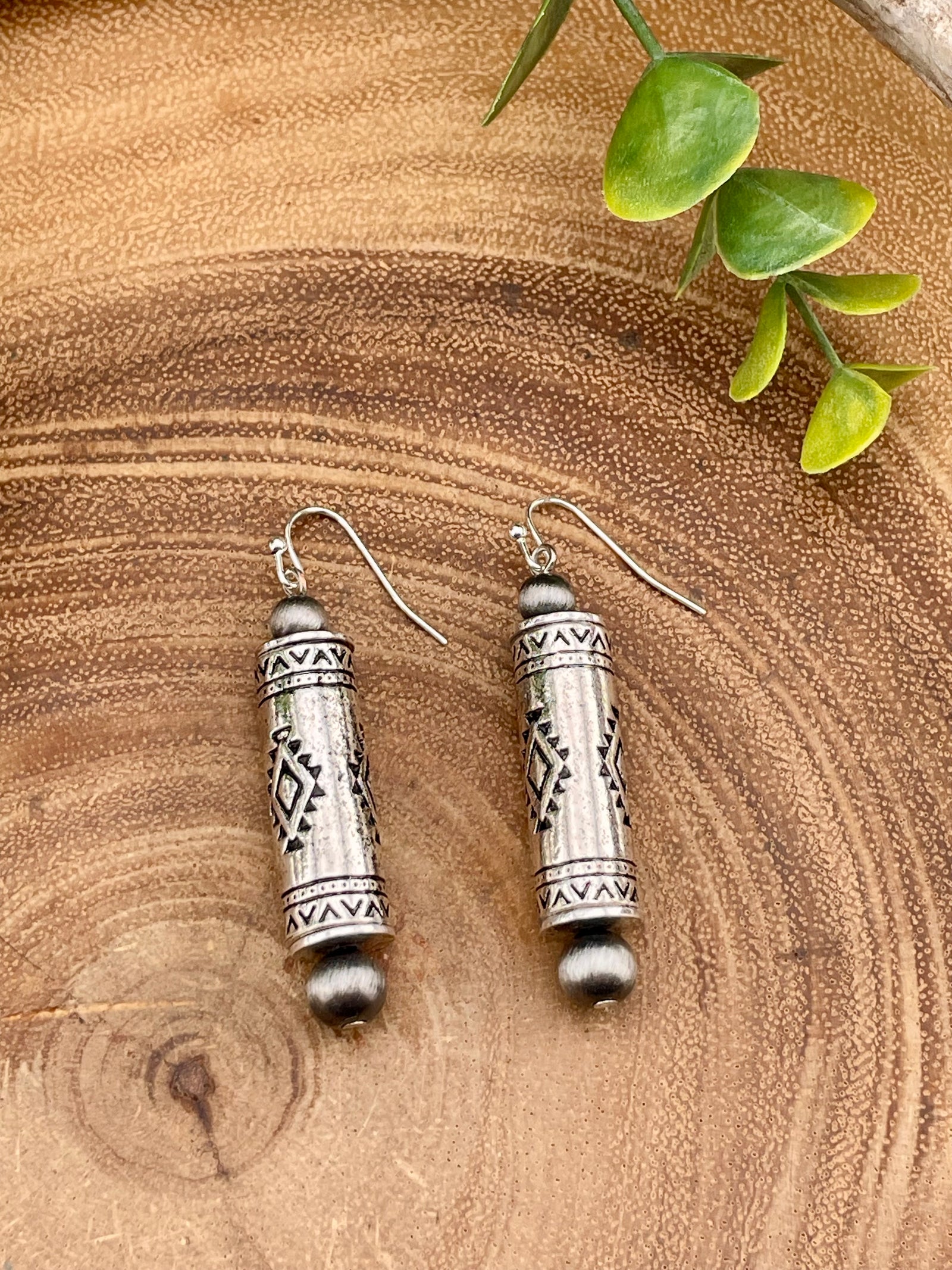 Silver barrel bead earrings on a wooden surface.