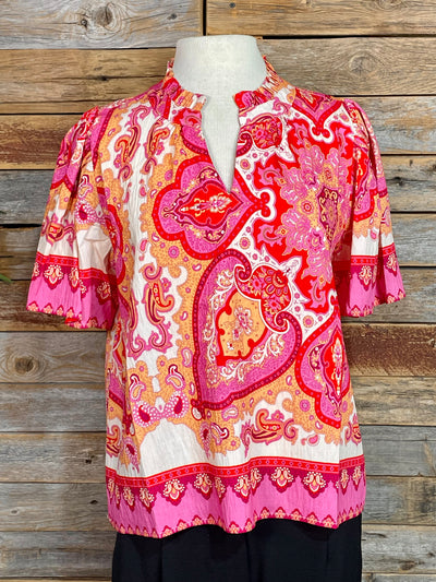 Colorful patterned blouse on a mannequin against a wooden background