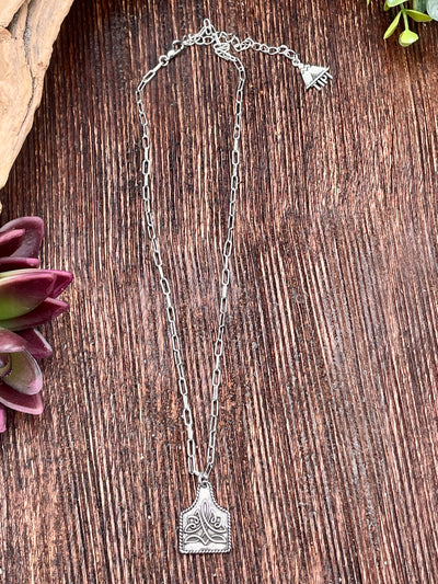 Silver necklace with a pendant on a wooden surface