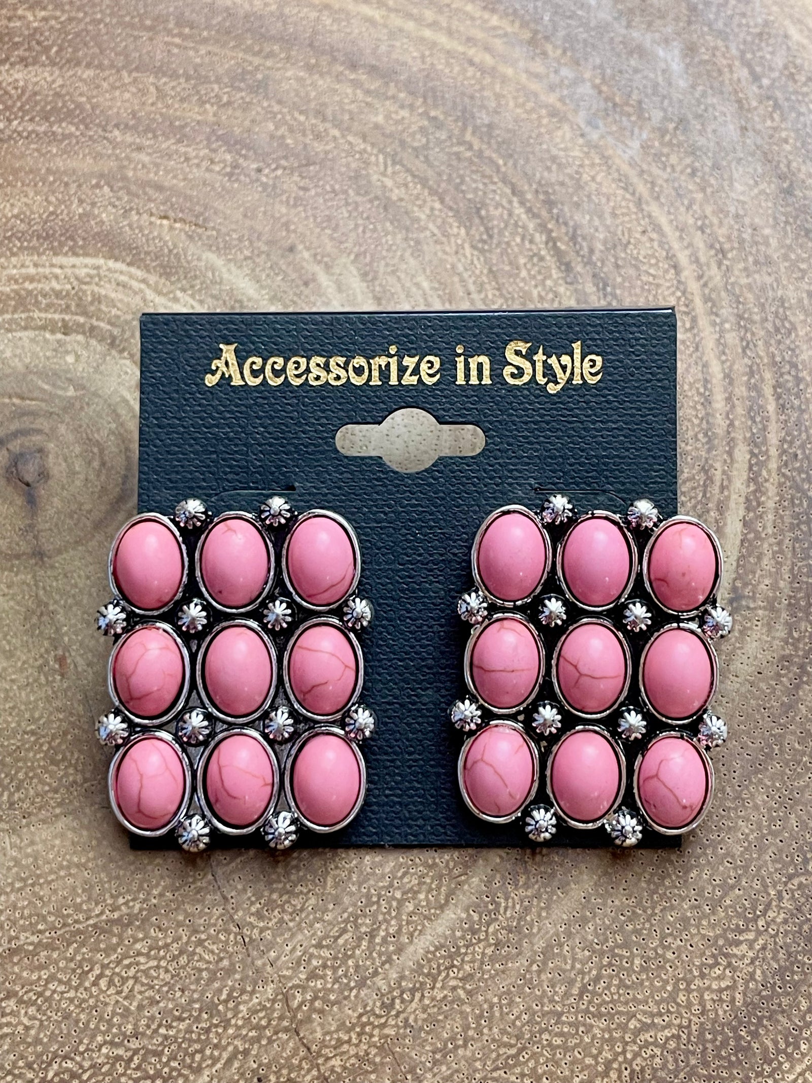 A pair of silver post earrings featuring pink stacked stones, displayed on a black card with the text 'Accessorize in Style'.