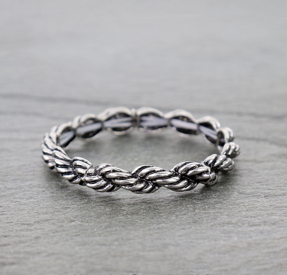 Silver braided ring on a gray surface.