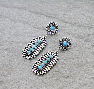 Pair of silver earrings with turquoise stones on a gray background
