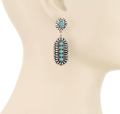 Turquoise and silver earrings on a mannequin with 'Blue Tortoise' branding.