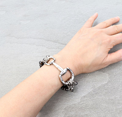 silver bit stretch bracelet on a person's wrist with a gray background