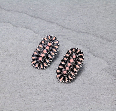 Pair of earrings with pink stones on a gray textured background
