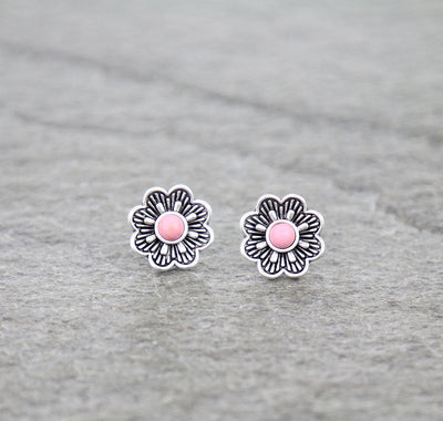 Flower-shaped earrings with pink centers on a gray background
