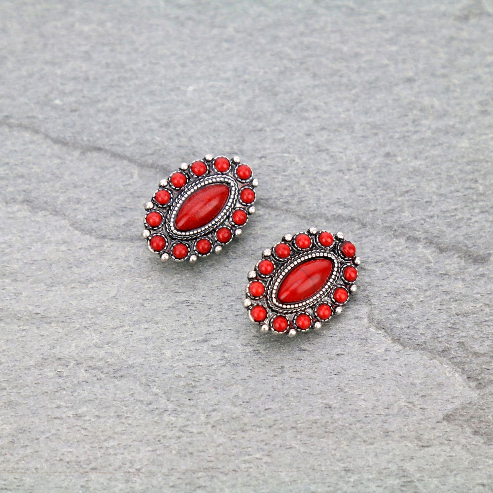 Pair of red earrings with silver accents on a gray surface