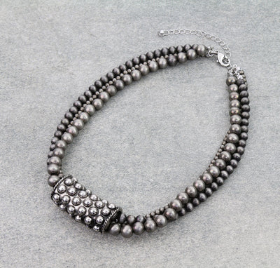 Necklace with silver beads on a light gray background
