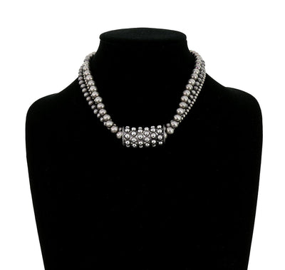 Silver beaded necklace on a black mannequin bust.