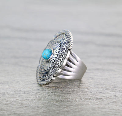 Concho ring with turquoise center on a gray background