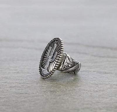 Silver ring with intricate design on a gray surface