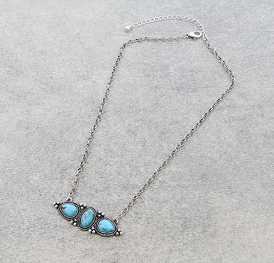 turquoise 3 stone necklace on a gray background