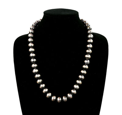Silver beaded necklace on a black mannequin against a white background