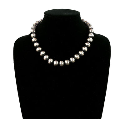 Silver pearl necklace on a black mannequin bust with a white background