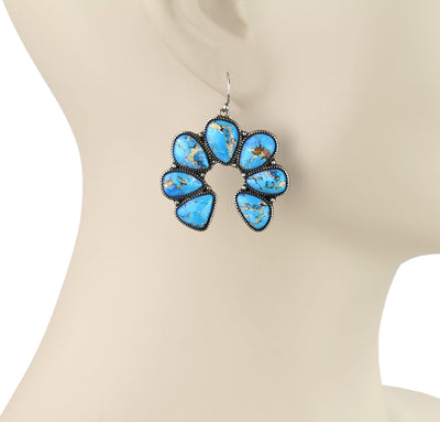 Turquoise earrings on a mannequin.