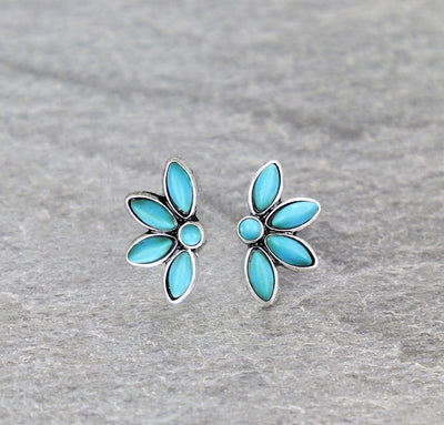 A pair of silver post earrings with turquoise stone accents, designed in a floral pattern, on a gray background