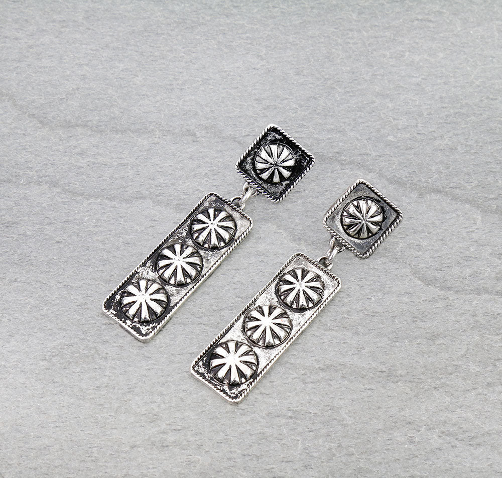 Silver earrings with star-like designs on a gray background
