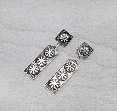 Silver earrings with star-like designs on a gray background