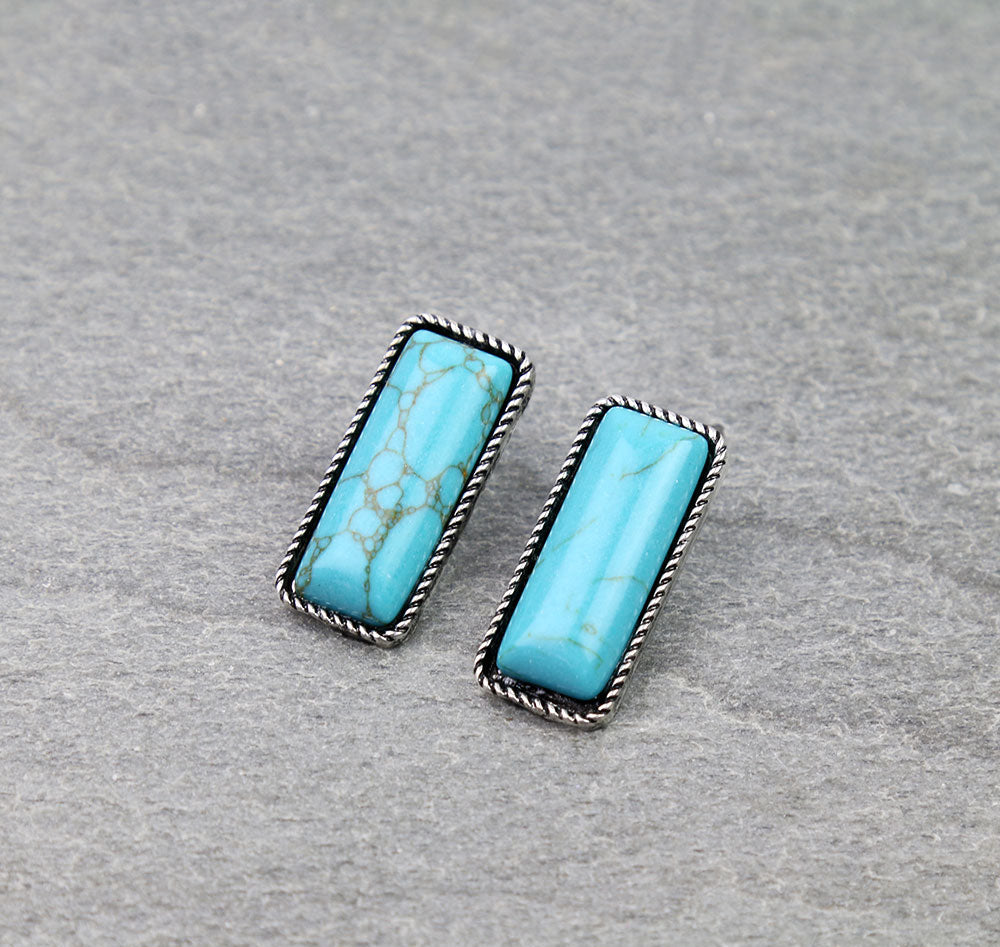 Pair of turquoise earrings with silver frames on a gray background