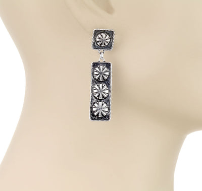 Silver earrings on a mannequin with 'Blue Tortoise' branding.