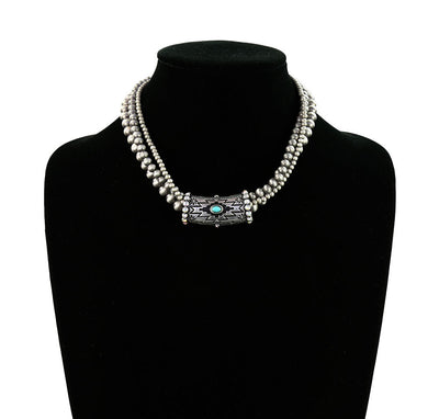 Necklace with a central turquoise stone on a black mannequin against a white background