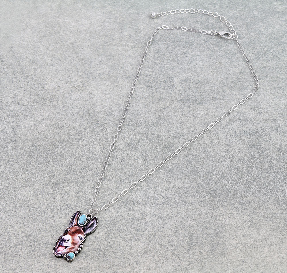 Silver necklace with laughing donkey pendant on gray background.