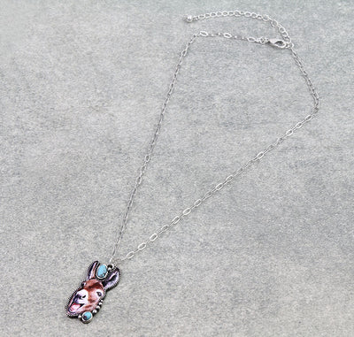 Silver necklace with laughing donkey pendant on gray background.