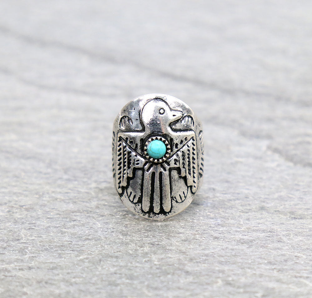 Silver ring with thunderbird design and turquoise stone on a gray background