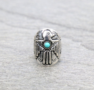 Silver ring with thunderbird design and turquoise stone on a gray background