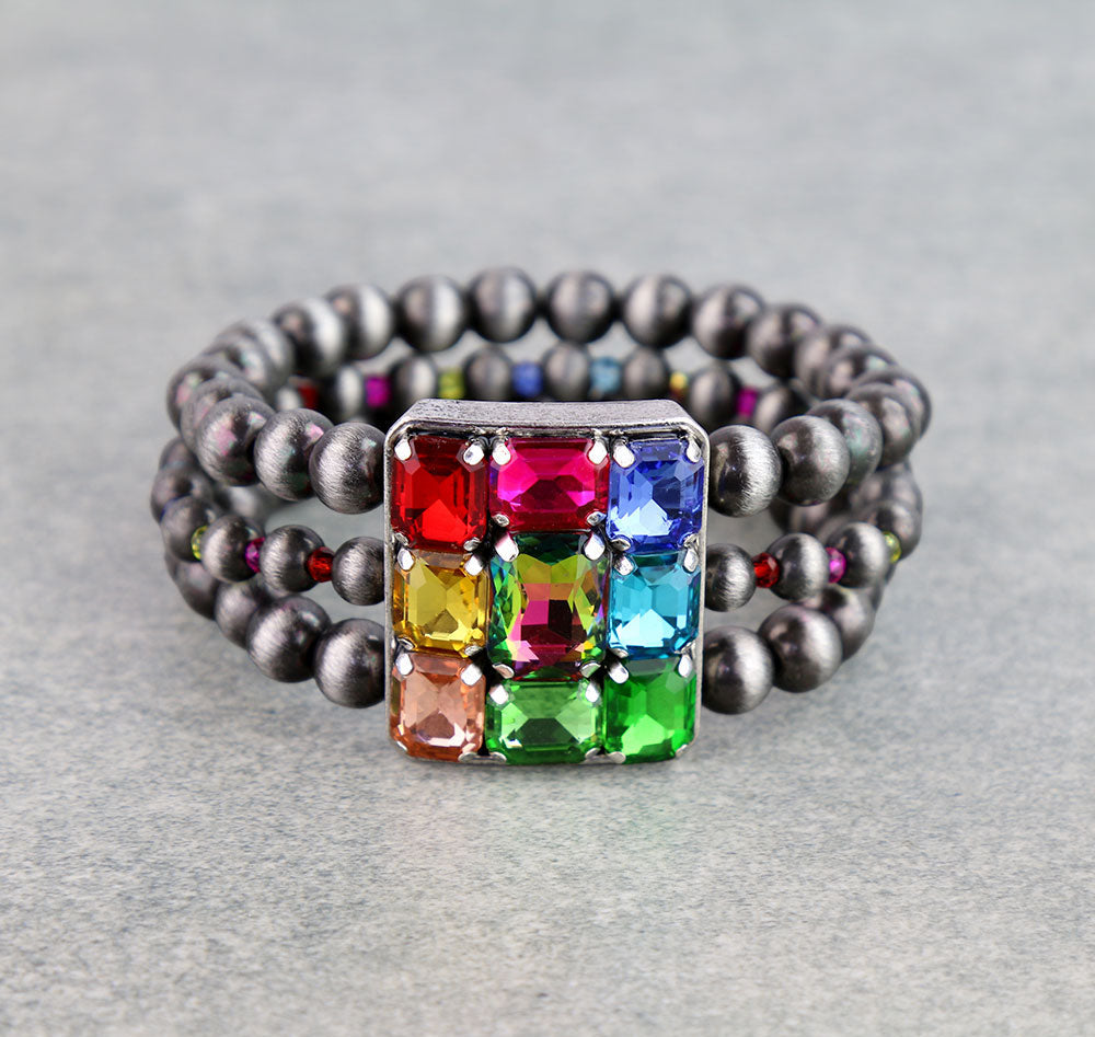 triple strand multi color rhinestone stretch bracelet on a gray background