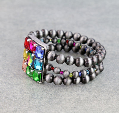 triple strand multi color rhinestone stretch bracelet on a gray background