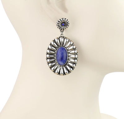 Silver earring with a blue gemstone on a mannequin bust, branded 'Blue Tortoise'.