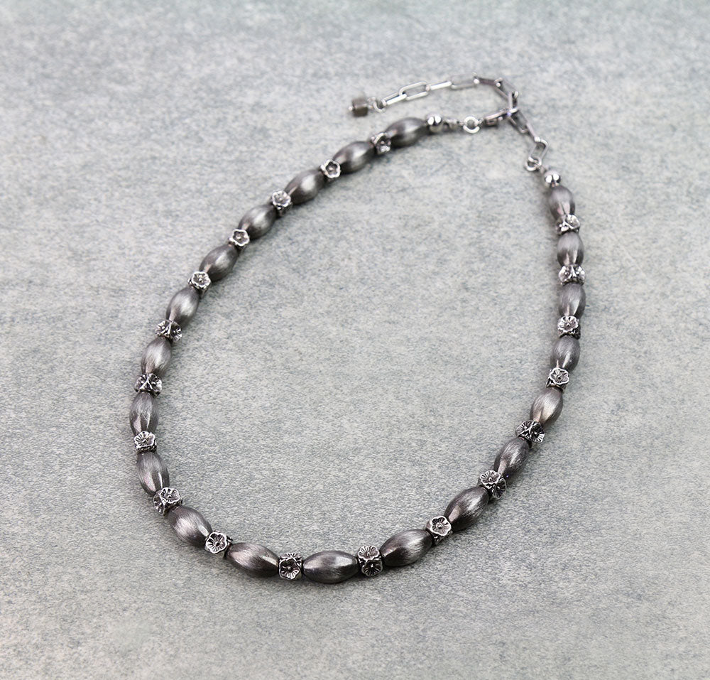 Necklace with gray beads and silver clasp on a light gray background